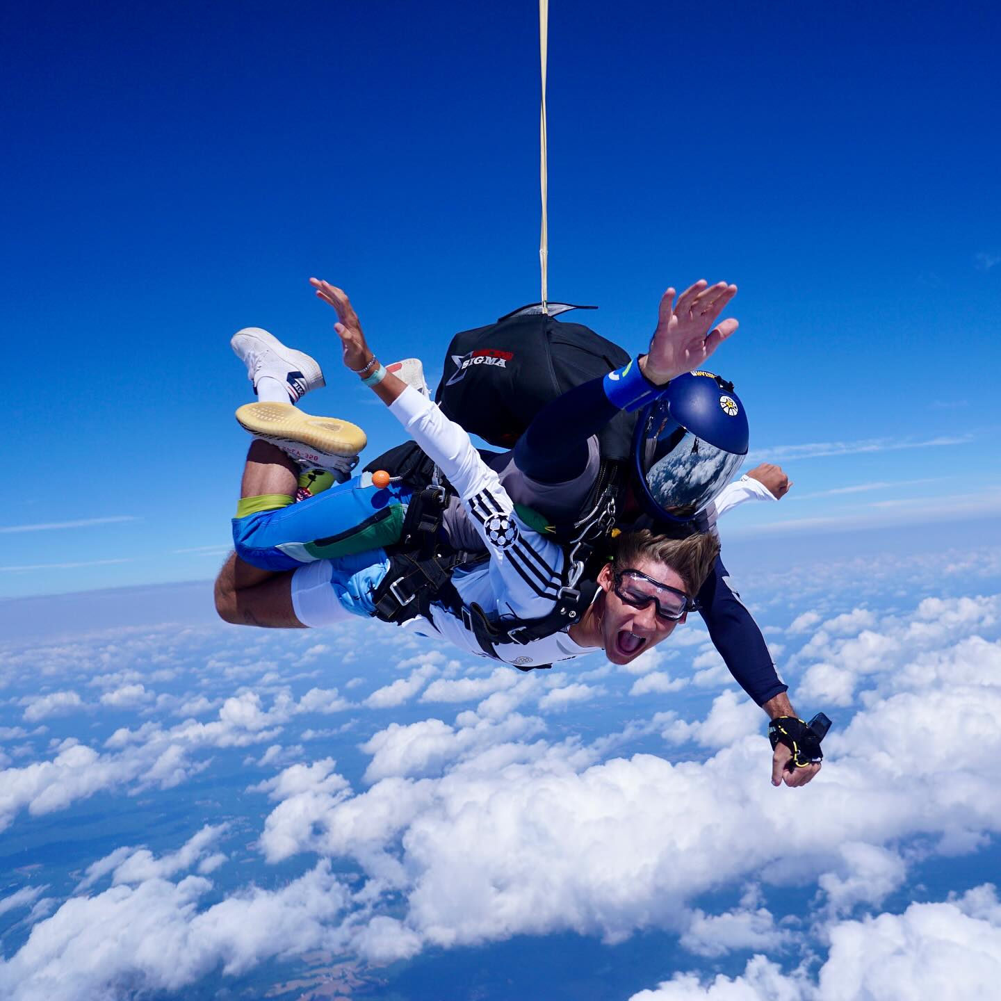 tandem skydivers in freefall, one with a hand mounted camera